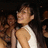 A pixelated static image shows a person in a white sleeveless top against a dark background with blurred figures.