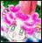 Pixelated image of pink and purple flowers with green foliage in the background, rendered in a low-resolution, blocky style.