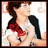 Pixelated image of a person with dark hair tied in a ponytail, wearing a white top with black sleeves and a red bow, against a light background.