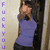 A person in a purple top and dark pants stands against a light background with vertical purple text reading "FUCK YOU" on the left side.