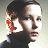 Pixelated image of a person with short dark hair wearing a dark shirt, holding a red and orange object near their ear.