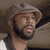 Static 50x50 pixel icon showing a man with a beard and cap in low-resolution grayscale tones, cropped to focus on upper face and shoulder against dark background.