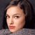 Pixelated close-up of a person's face with dark hair, light skin, and red lips against a dark background.