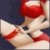 Pixelated close-up of a figure with red hair and a red headband, wearing a white garment with red accents, against a dark blue background.