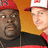 Pixelated image of two men wearing red and white caps with a logo, standing against an orange background with bold red text reading "DO WORK SON!!!".