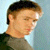 A pixelated image of a person with short brown hair wearing a dark shirt, positioned next to text fragments on a light blue background.