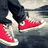 Four- shows red sneakers, white earbuds, red star, and partial text on black background