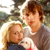 Pixelated static image of two people and a small dog in an outdoor setting with blurred greenery background.