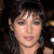 Pixelated close-up of a person with dark hair and light skin, wearing a dark top against a dark background.