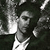 Pixelated grayscale image of a person with dark hair and a light-colored shirt, partially obscured by a bright light source on the left side.
