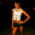 Pixelated figure in white tank top and dark shorts stands with one hand on hip against black background.