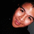 Pixelated close-up of a person's face with light skin, dark eyes, and pink lips against black background.