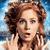A pixelated close-up of a person with curly brown hair, light skin, and blue eyes, hands raised near the face against a blue gradient background.