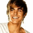 Pixelated close-up of a smiling person with brown hair and light skin, wearing a white shirt against a plain background.