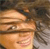 A pixelated close-up of a person's face with light skin tone, brown hair, and a neutral expression, set against a blurred background.