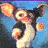 Pixelated gremlin character with large ears and orange hands against blue background, next to green text reading 'OriginalIcons.com' on dark green backdrop.