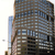 Pixelated static image of a multi-story building with blue and brown tones, partially obscured by a lighter adjacent structure on the left.