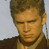 Static pixelated image of a person's face and upper torso with brown hair, wearing a dark jacket over a light shirt against a plain background.