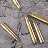Pixelated image of multiple golden-brown curved objects resembling bones or sticks scattered on a gray textured background.
