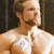 A pixelated static image shows a shirtless person with light brown hair and facial stubble, standing against a dark background.