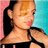 Pixelated image of a person with long dark hair tied back, wearing a black top against pink and cyan background.