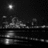 Black-and-white animated scene of a cityscape at night with water reflections, featuring subtle changes in light and motion across four