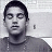Pixelated grayscale portrait of a person with short dark hair, neutral expression, and visible neck against light background.