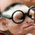 A split-screen image with a pixelated close-up of an elderly person wearing glasses on the left and a cartoon monkey character laughing on the right.