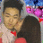 Two people embrace with closed eyes; one wears a light pink shirt and red collar, the other has long dark hair. Background features blue and purple floral shapes.