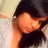 Pixelated image of a person with dark hair covering their face, wearing a black top against a light background.