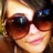 A pixelated close-up of a person wearing dark sunglasses with reflective lenses showing light reflections, smiling slightly.