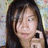 A pixelated close-up of a person with long dark hair holding a black mobile phone to their ear against a blurred multicolored background.