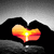 A heart-shaped icon with a gradient from yellow to red, held by two black hands against a gray background.