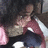 Pixelated static image of a person in a red shirt with white accents, dark pants, and light-colored shoes, holding a pink object near their face.