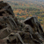 Static pixelated image of rocky terrain with muted earth tones and a distant horizon under a pale sky.