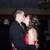 Pixelated image of two figures in a close embrace, one figure wearing dark clothing with red accents and the other in light-colored attire against a dark background.