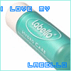 A teal cylindrical tube with white cap labeled 'Labello' and 'Hydro Care', surrounded by blue pixelated text reading 'I LOVE MY LABELLO'.