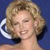 Pixelated close-up of a person with curly blonde hair, closed eyes, and a smiling mouth against a solid blue background.