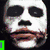 Pixelated image of a character with white face paint, black eye makeup, and red lips holding a white cloth against a light background.