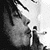 Black-and-white pixelated icon showing a partial profile of a person with dark hair and facial features, including an eye, nose, mouth, and ear, against a light background with visible dithering and grayscale shading.