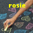A hand holding a small object against a patterned background with yellow text labels.