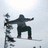 Pixelated static image of two figures in dynamic poses against a light background, one figure holding an object above its head.