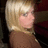 Pixelated static image of a person with light brown hair and a brown top against a dark background.