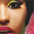 Close-up of a person's face showing eye with yellow eyeliner, nose, lips, and pink clothing against dark background.