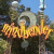 Pixelated image with fiery orange-yellow text reading 'aim-bender4' over a blurred background of green foliage and blue sky.