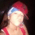 A person wearing a red cap with blue trim and red straps, positioned against a dark background with a light gray area on the right.