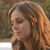 Pixelated close-up of a person with long brown hair, closed eyes, and a neutral expression against a blurred background.