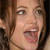 A pixelated close-up of a person with light brown hair, showing eyes, nose, mouth, and part of the neck against a dark background.