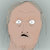 Pixelated close-up of a bald figure with wide eyes and a small mouth against a light gray background.