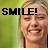A pixelated image shows a person with light hair smiling broadly, overlaid with bold black text reading 'SMILE!' against a green gradient background.